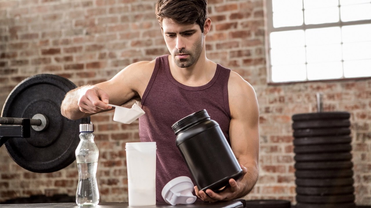 Buying guide for pre-workout supplements banner showing a man scooping pre-workout supplements into a shaker bottle